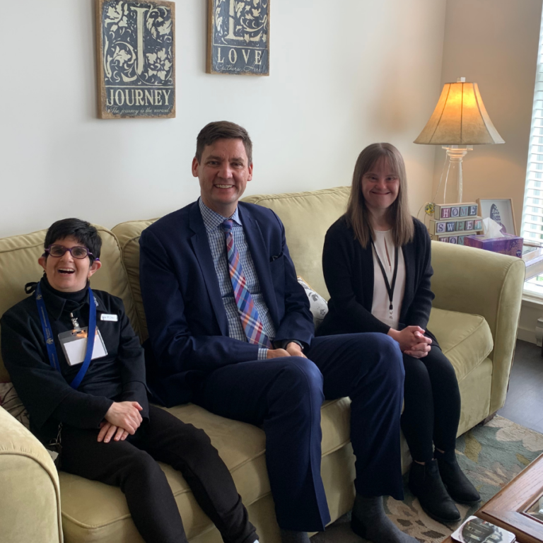 Self Advocates Michaela and Krista sit with David Eby inside their apartment at Chorus.